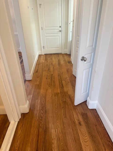 A hallway with hardwood floors and white doors in a house.