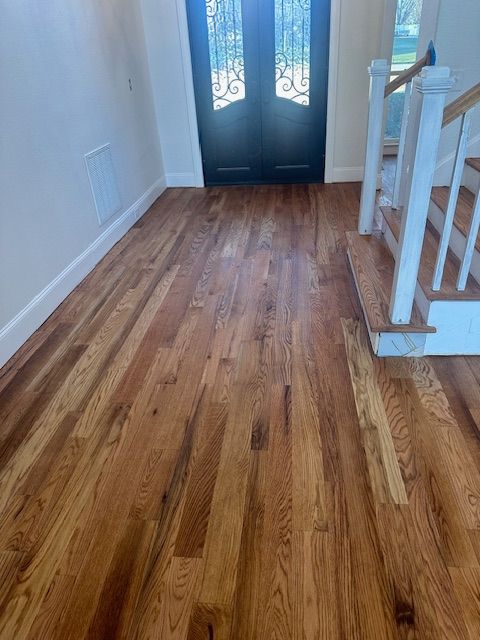 A hallway with hardwood floors and stairs in a house.