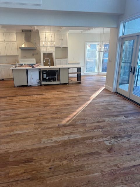 An empty kitchen with hardwood floors and white cabinets.