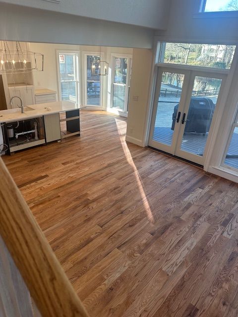 A living room with hardwood floors and a kitchen in the background.