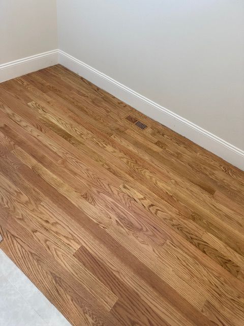 A close up of a wooden floor in a room with white trim.