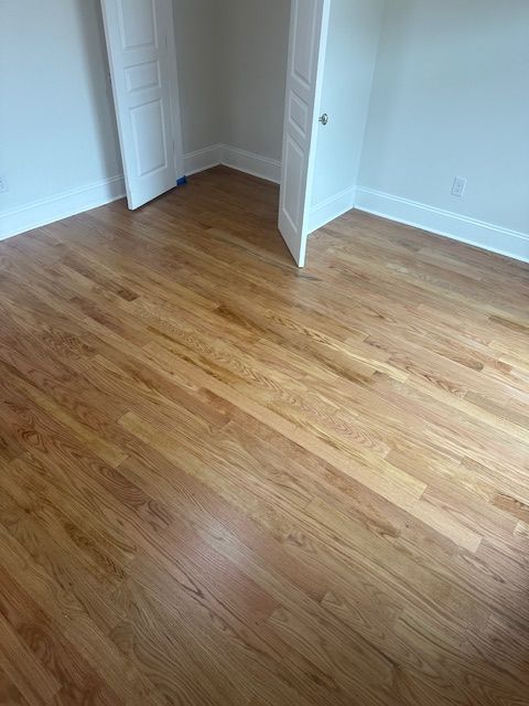 A bedroom with hardwood floors and white walls.
