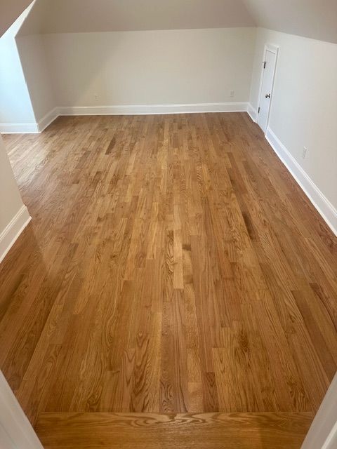 An empty room with hardwood floors and white trim.