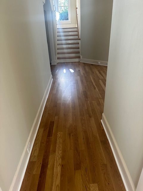 A hallway with hardwood floors and stairs in a house.