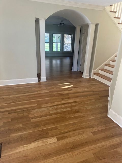 An empty room with hardwood floors and stairs in a house.