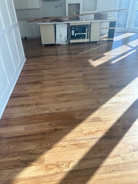 A kitchen with a wooden floor and white cabinets.