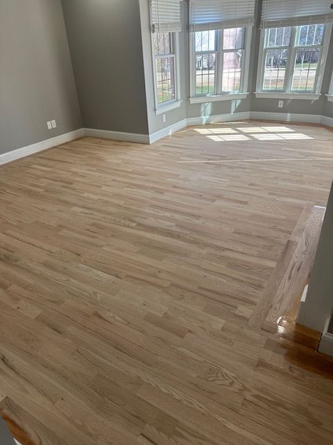 A living room with hardwood floors and a lot of windows.
