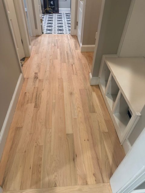 A hallway with hardwood floors and a bench.