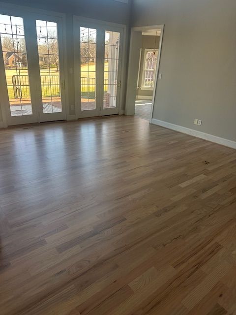 An empty living room with hardwood floors and sliding glass doors.