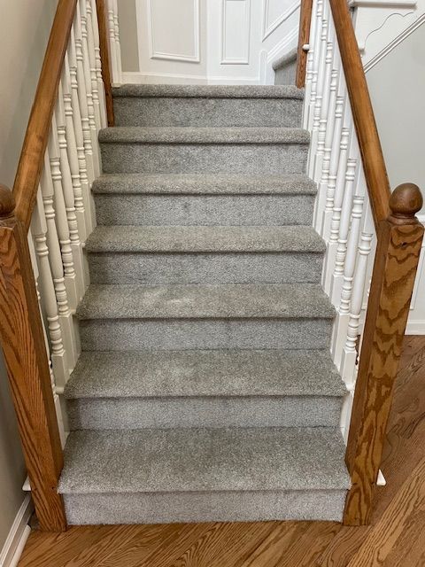 A set of stairs with carpeted steps and a wooden railing.