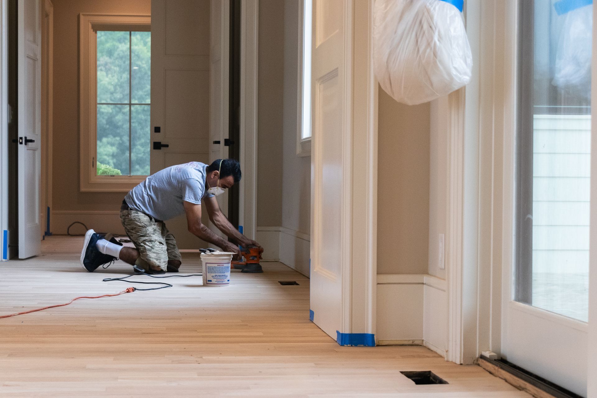 A man is kneeling on the floor in a hallway.