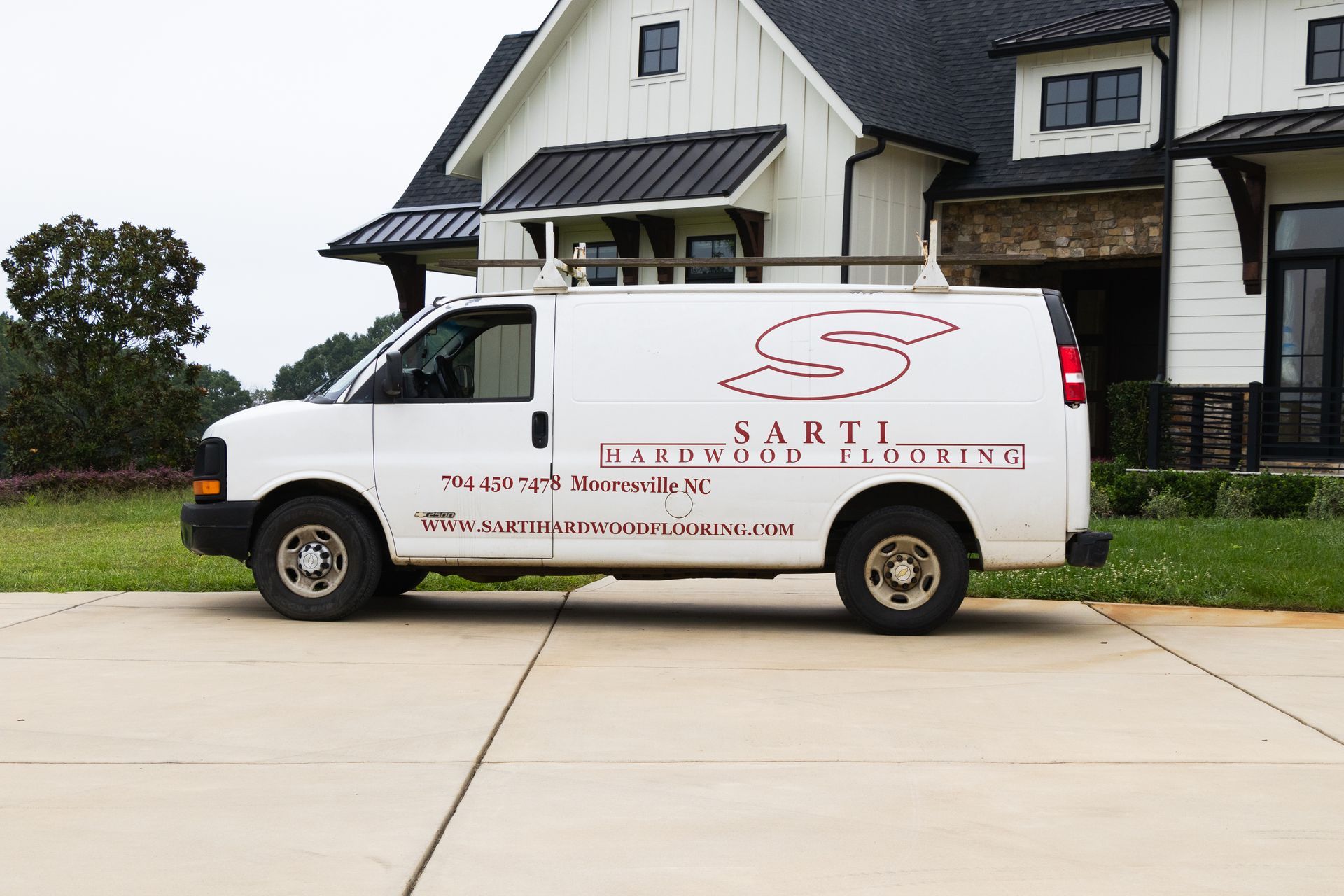 A white van is parked in front of a large white house