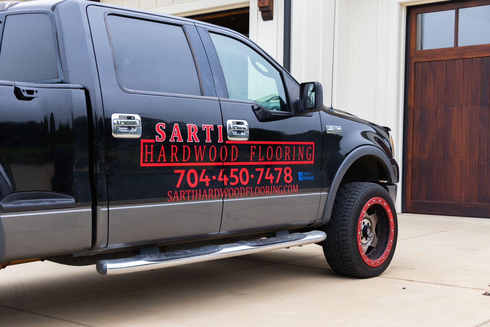 A black truck is parked in front of a garage door.