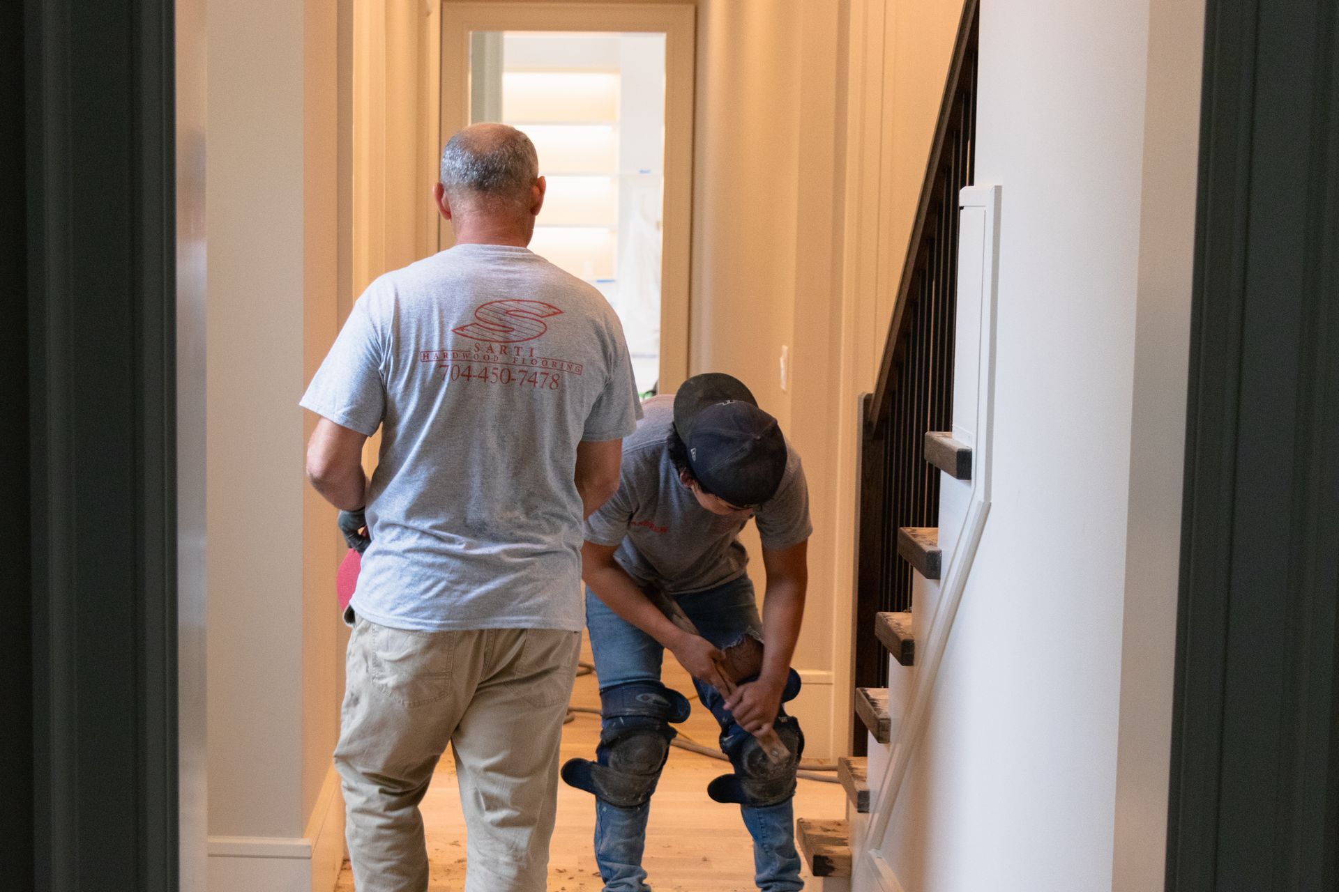 Two men are standing next to each other in a hallway.