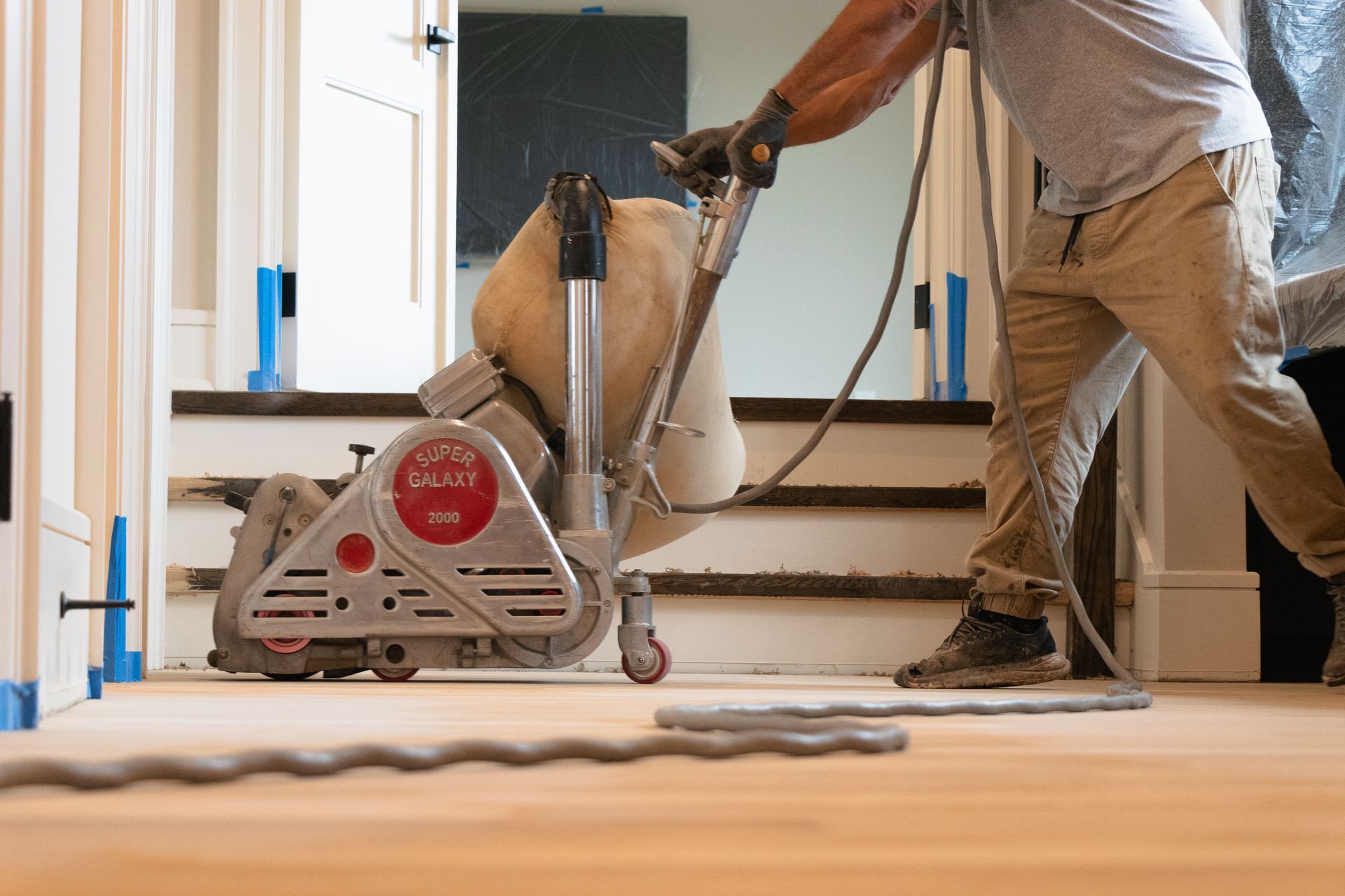 A man is sanding a wooden floor with a machine.