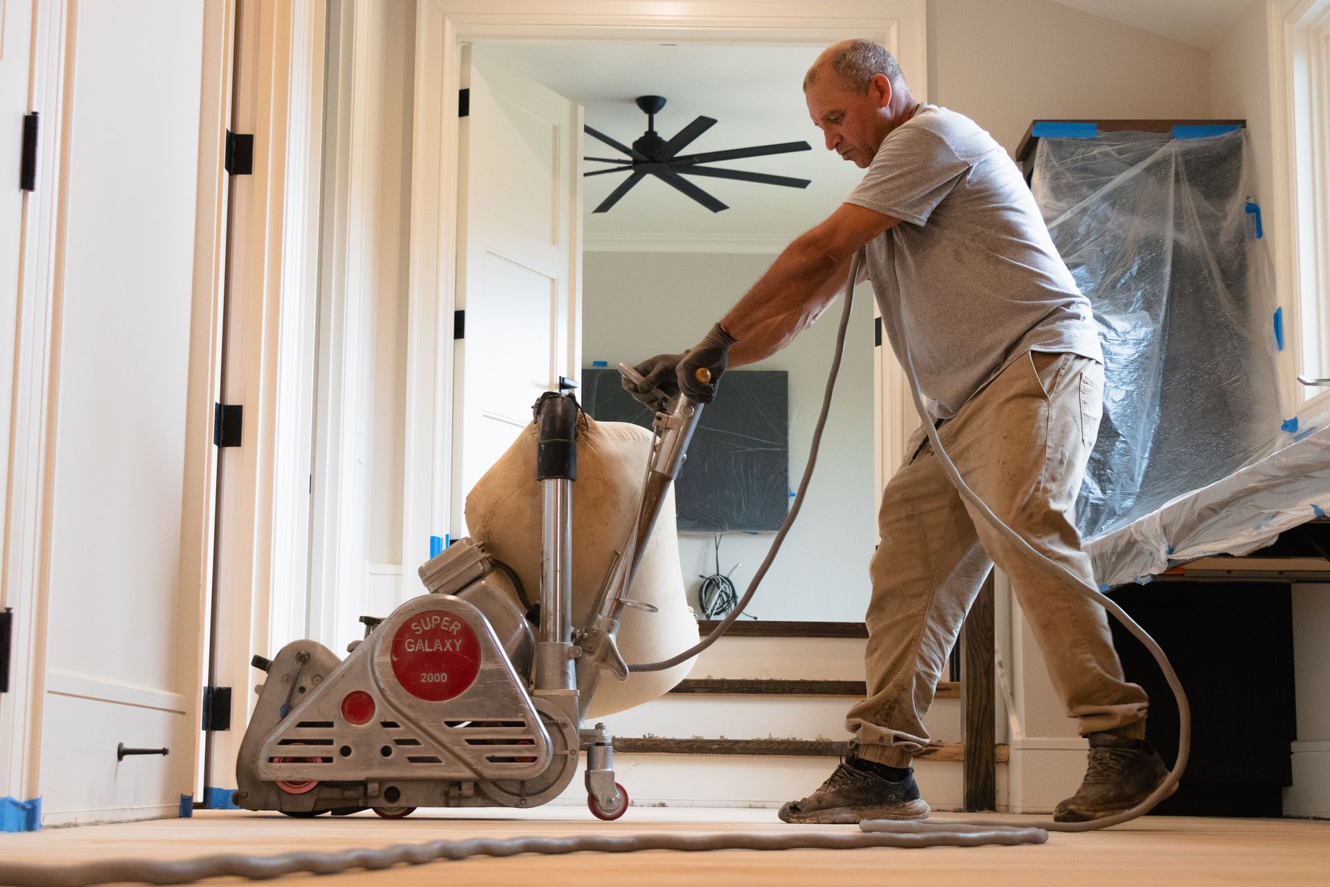A man is sanding a wooden floor with a machine.