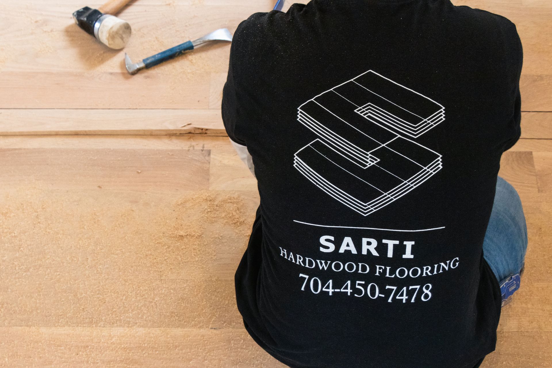 A person wearing a shirt that says sarti hardwood flooring