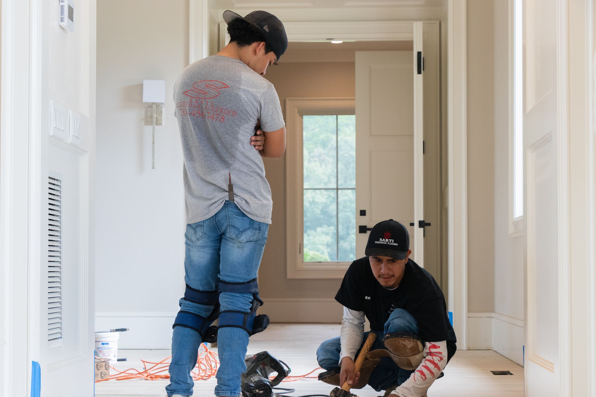 Two men are working on a floor in a room.