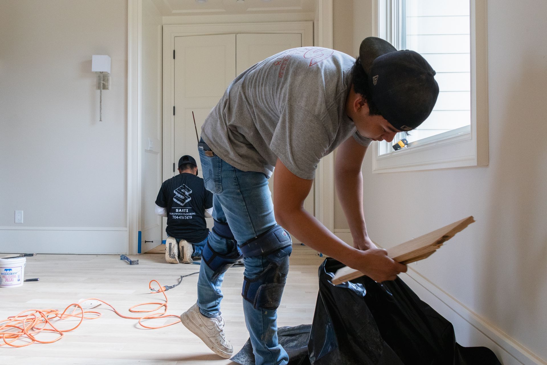 A man is working on a wooden floor in a room.