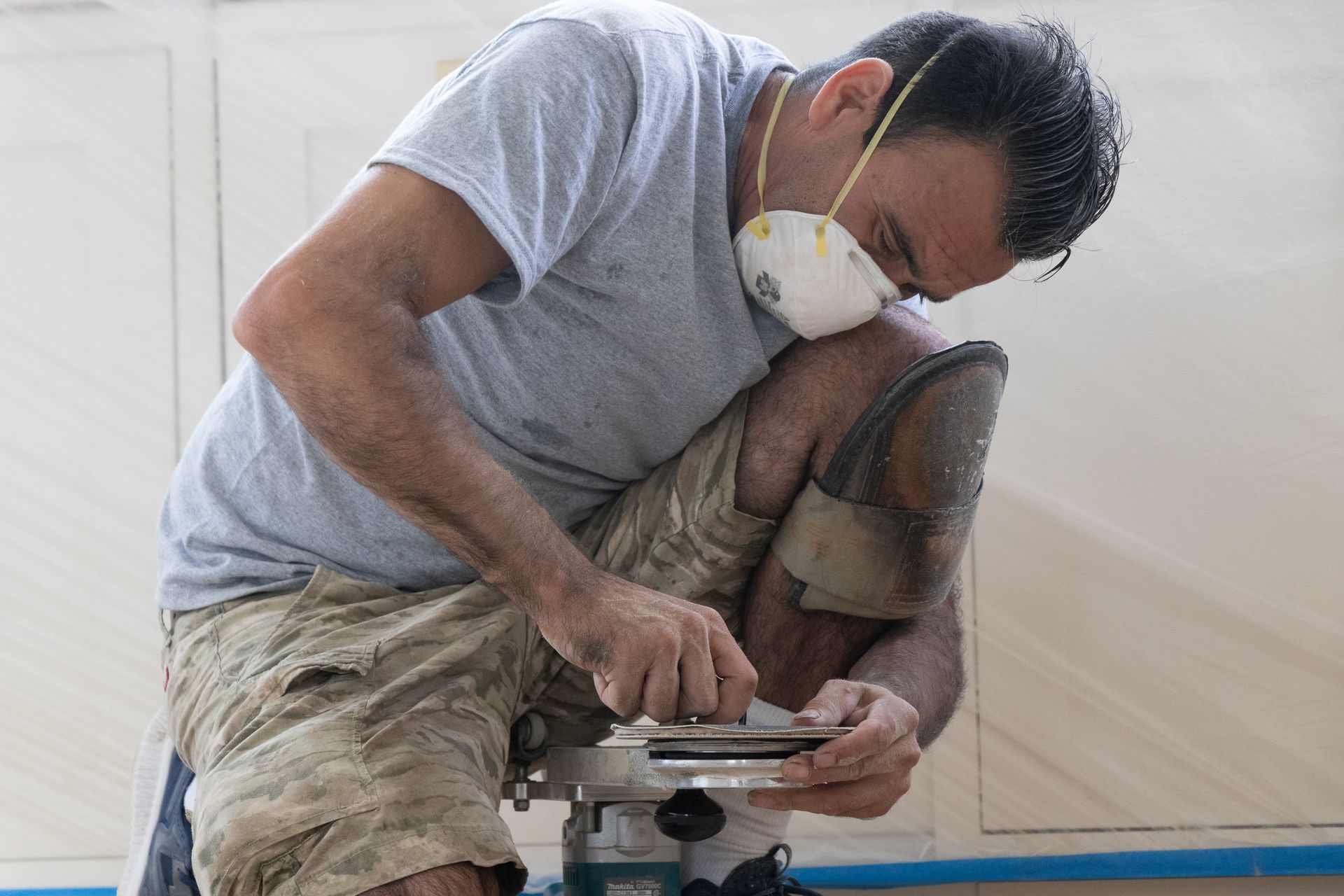 A man wearing a mask is working on a machine.