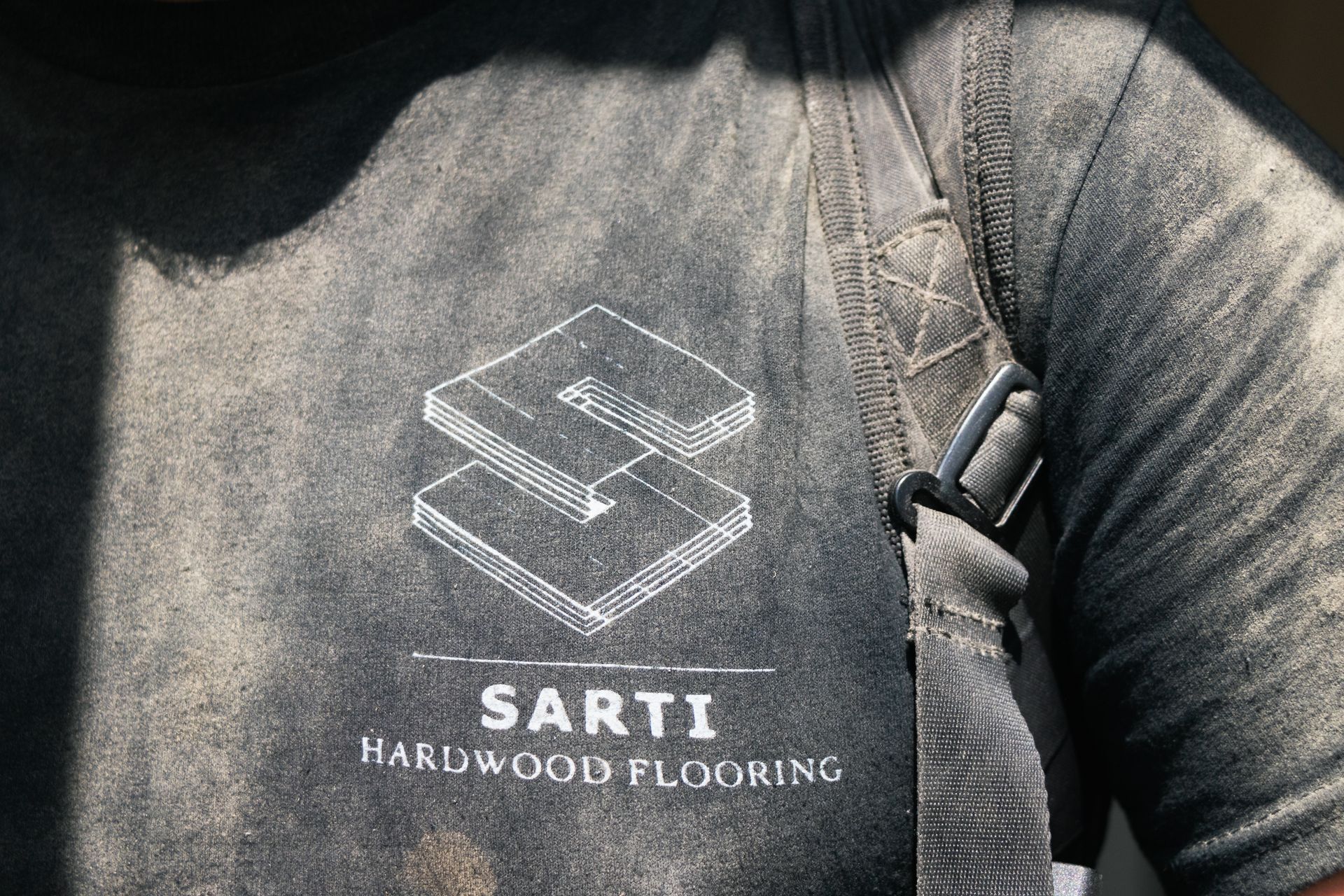 A person wearing a shirt that says ' sarti hardwood flooring ' on it