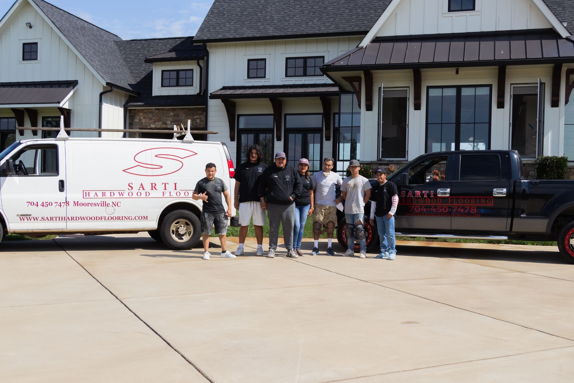 A group of people are posing for a picture in front of a large house.