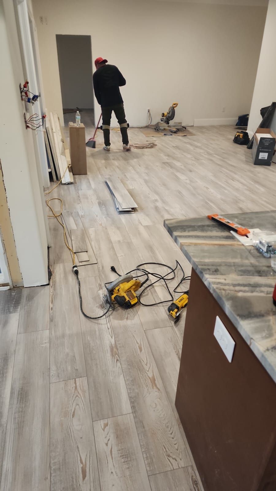 A man is standing on a wooden floor in a room.