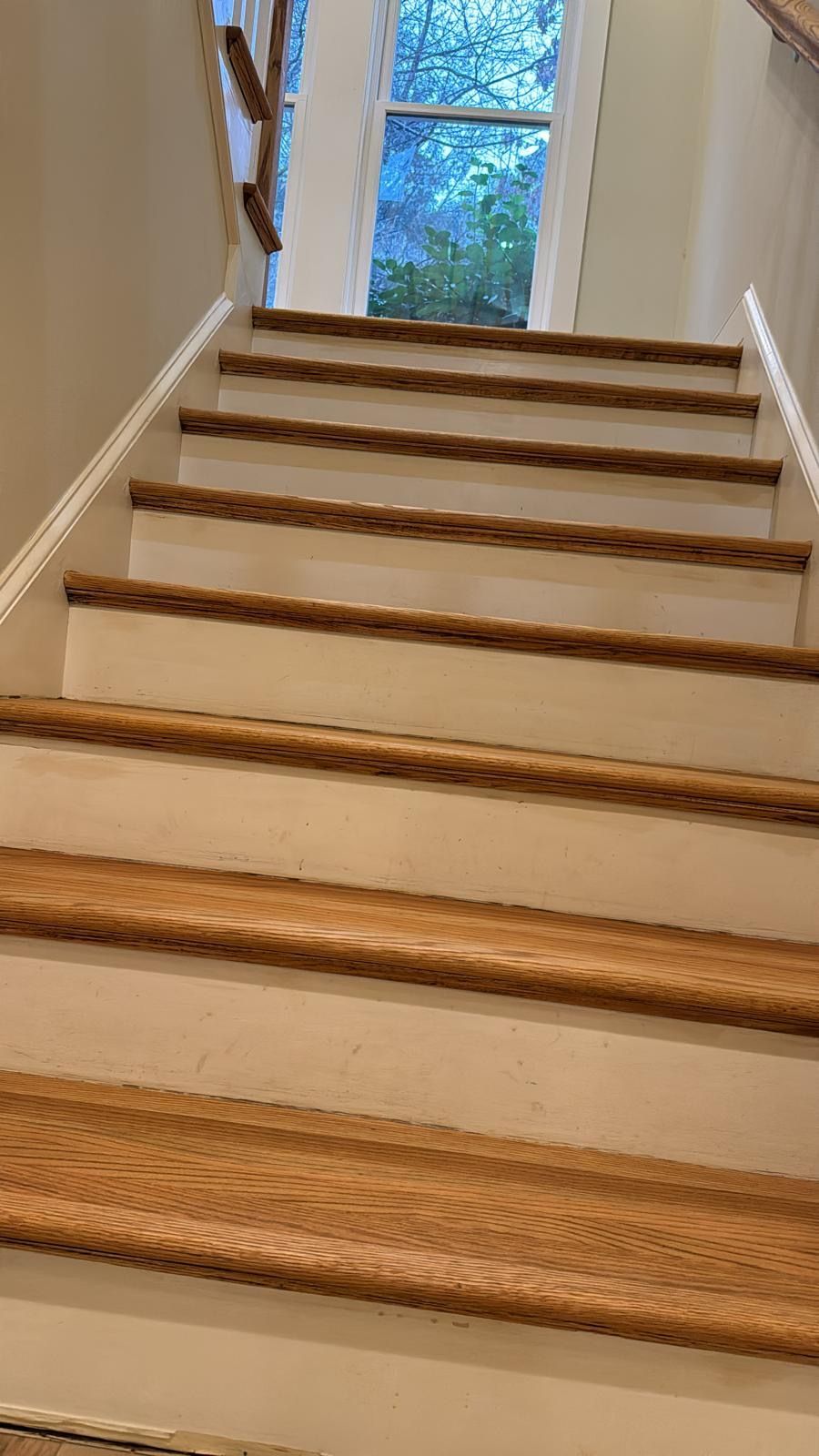 A set of white stairs with wooden steps leading up to a window.