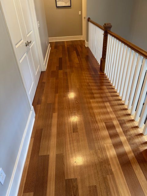 A hallway with hardwood floors and stairs in a house.