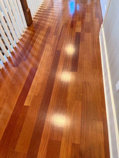 A hallway with a wooden floor and white railing.
