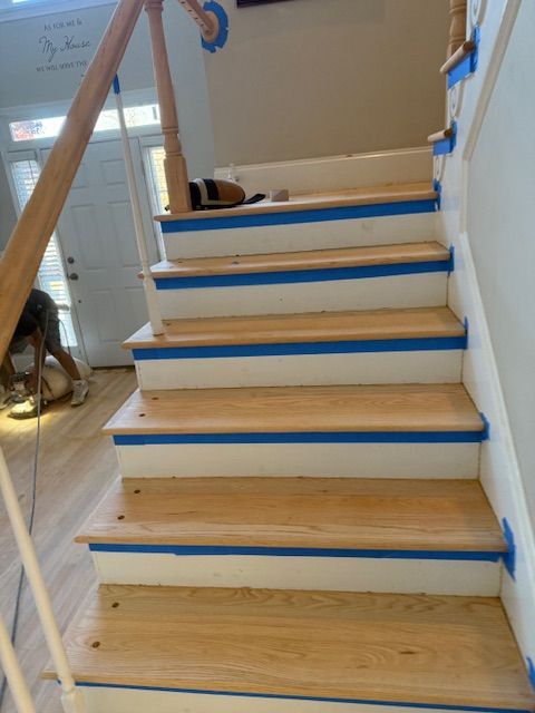 A staircase is being painted with blue tape