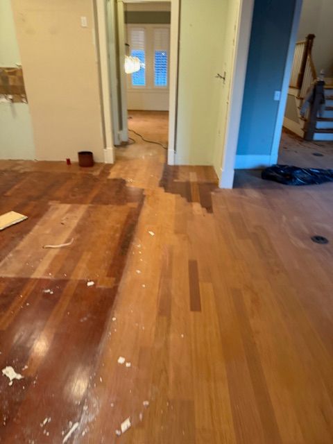 A wooden floor in a room with a staircase in the background