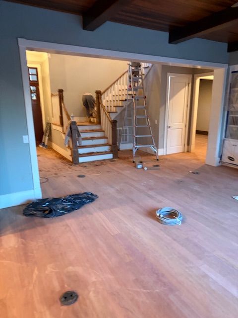 An empty room with a wooden floor and stairs in the background.