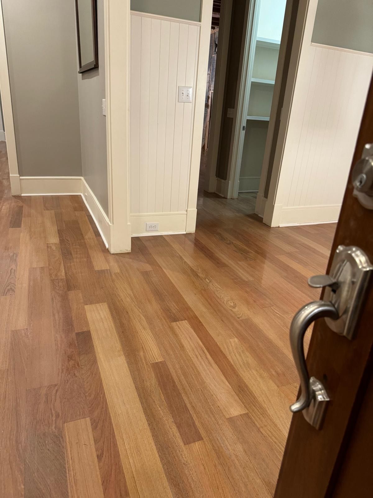 A hallway with hardwood floors and a door handle.