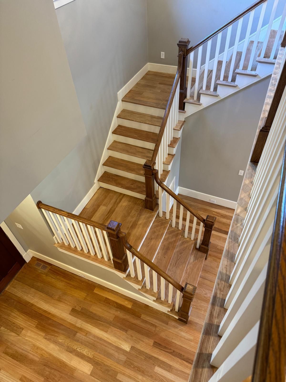 An aerial view of a wooden staircase with white railings in a house.