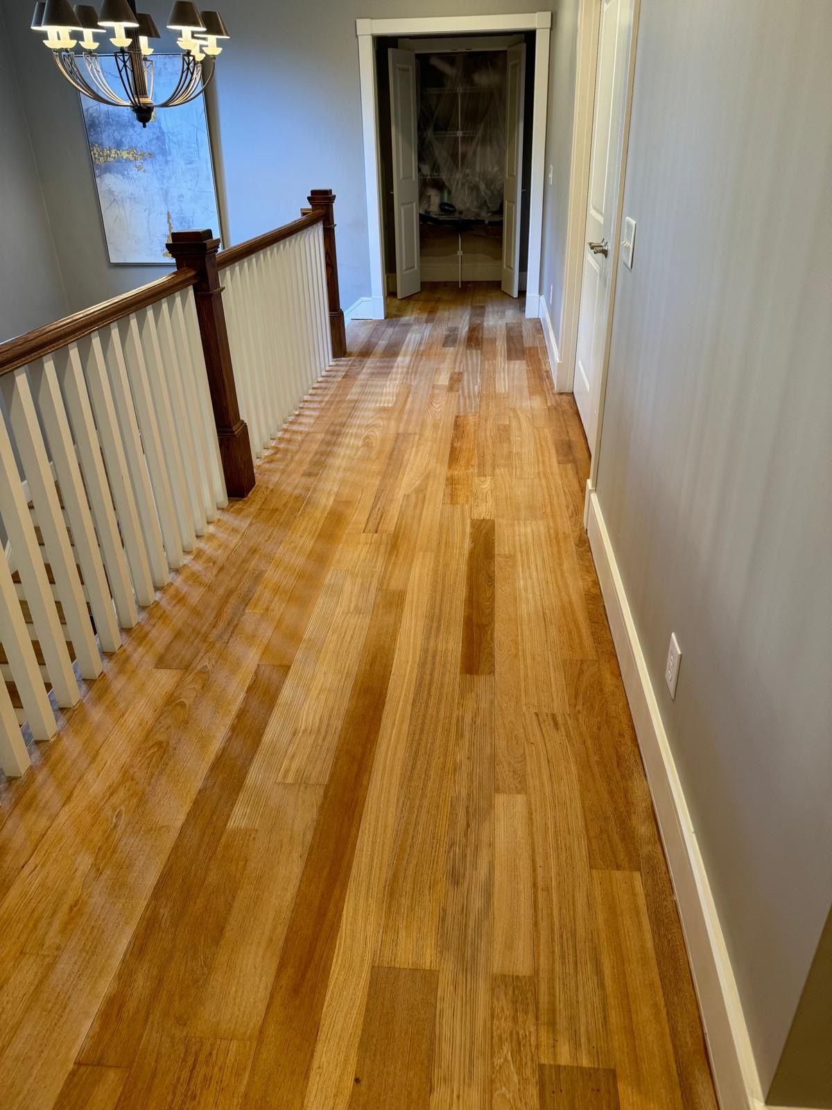 A hallway with hardwood floors and a staircase in a house.
