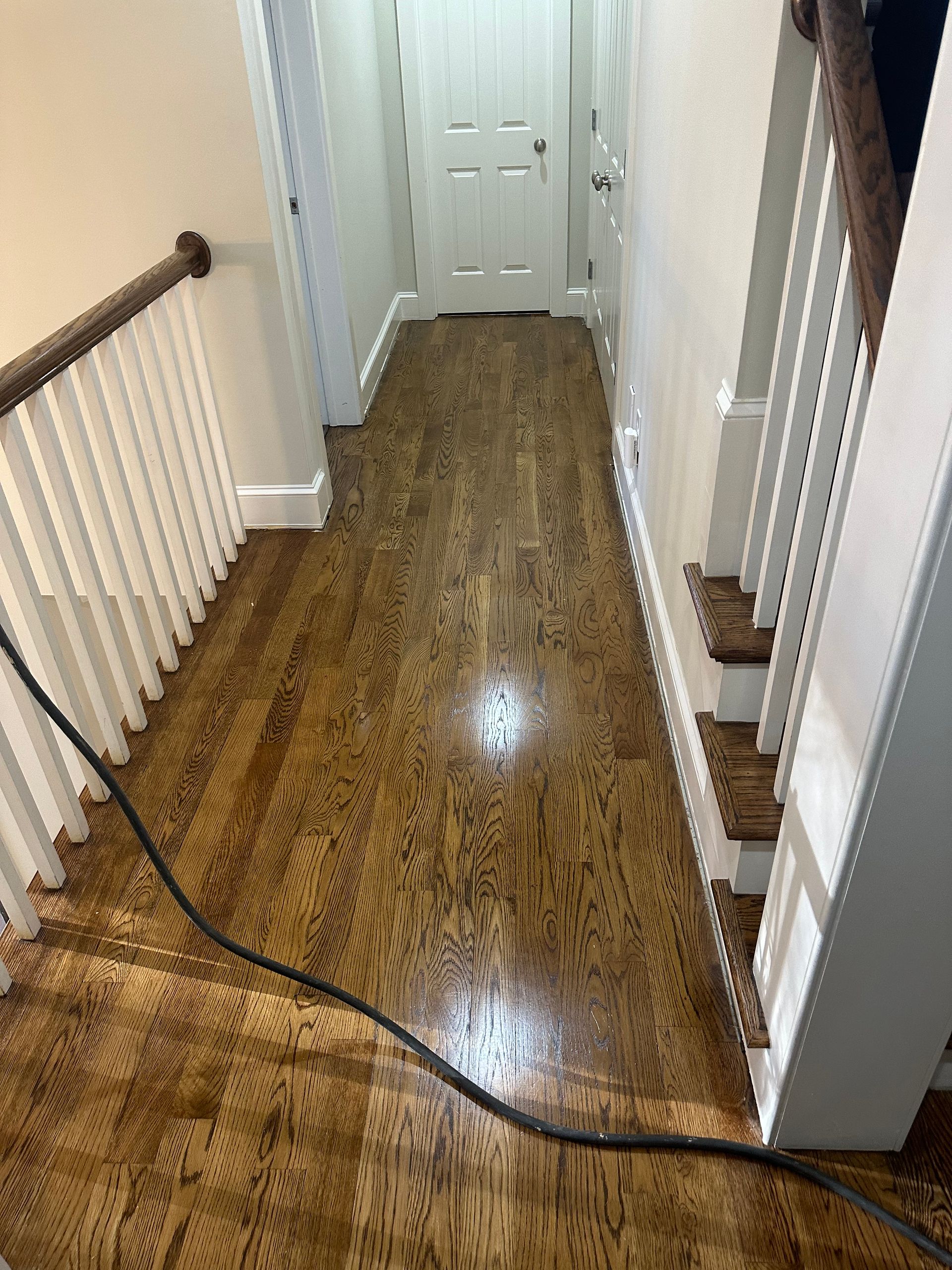A hallway with hardwood floors and stairs in a house.
