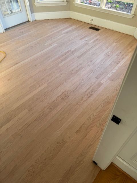 A living room with a wooden floor and a window.