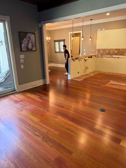 A man is standing on a wooden floor in a living room.