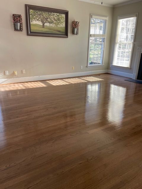 An empty living room with hardwood floors and a painting on the wall.