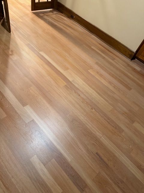 A wooden floor in a hallway with a door in the background.