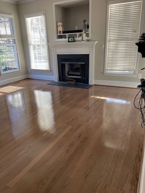 An empty living room with hardwood floors and a fireplace.