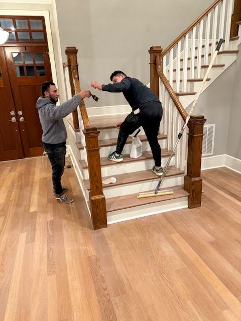 Two men are working on a set of stairs in a living room.