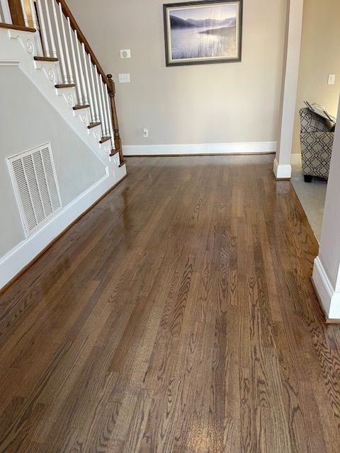 A living room with hardwood floors and stairs and a picture on the wall.