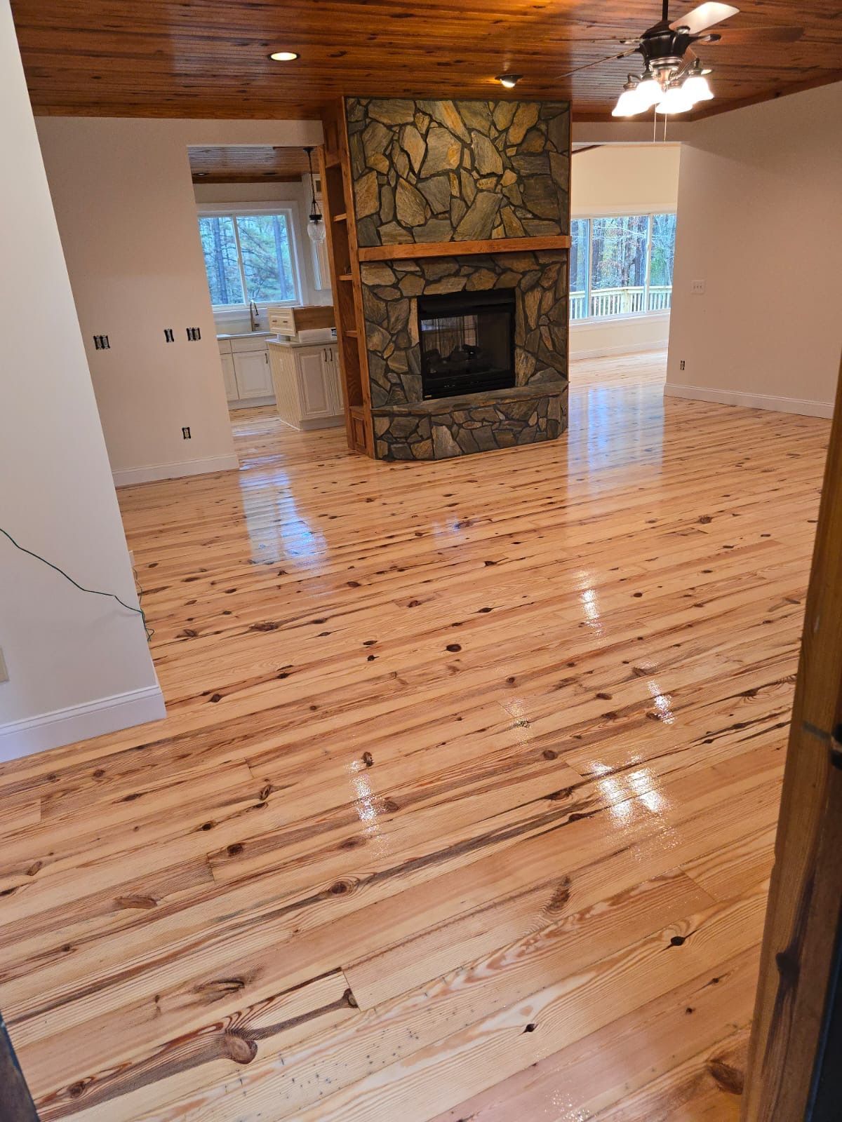 A living room with a wooden floor and a stone fireplace.