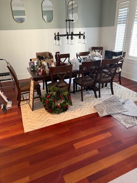 A dining room with a table and chairs and a wreath on the floor.