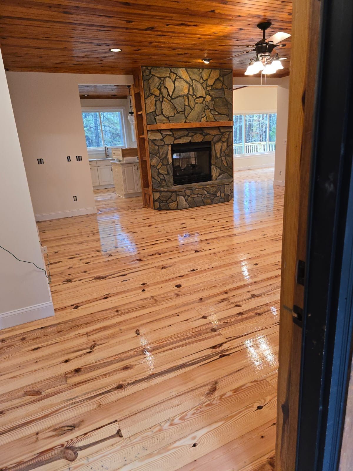 A living room with wooden floors and a stone fireplace.