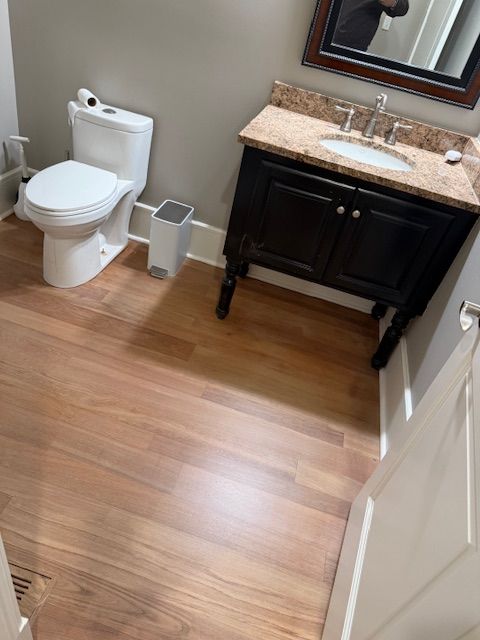 A bathroom with a toilet , sink and mirror.
