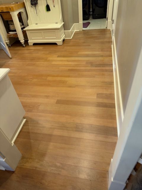 A hallway with a wooden floor and stairs in a house.