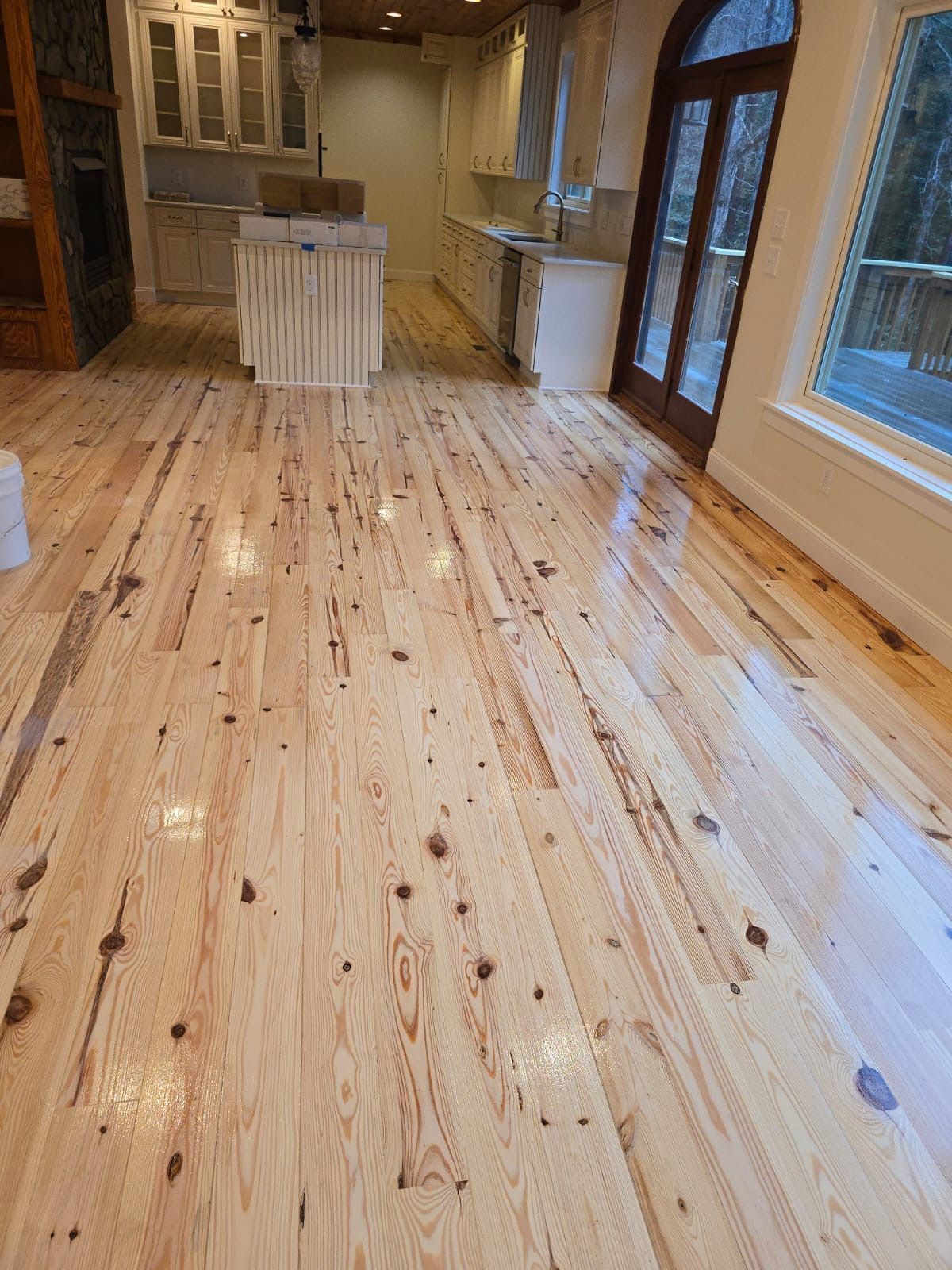 A kitchen with a wooden floor and a large window.